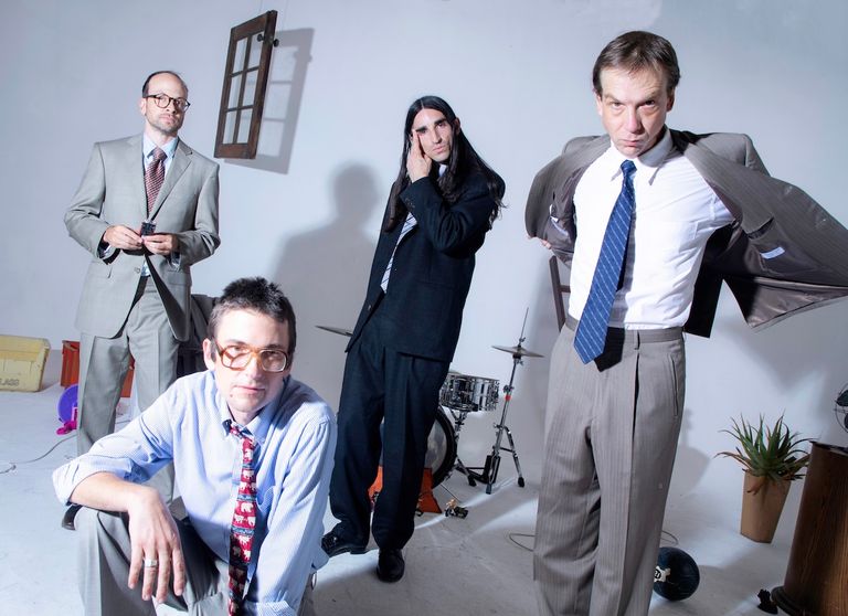 Promotional photo of indie rock band DIIV posing in suits inside a brightly lit studio.